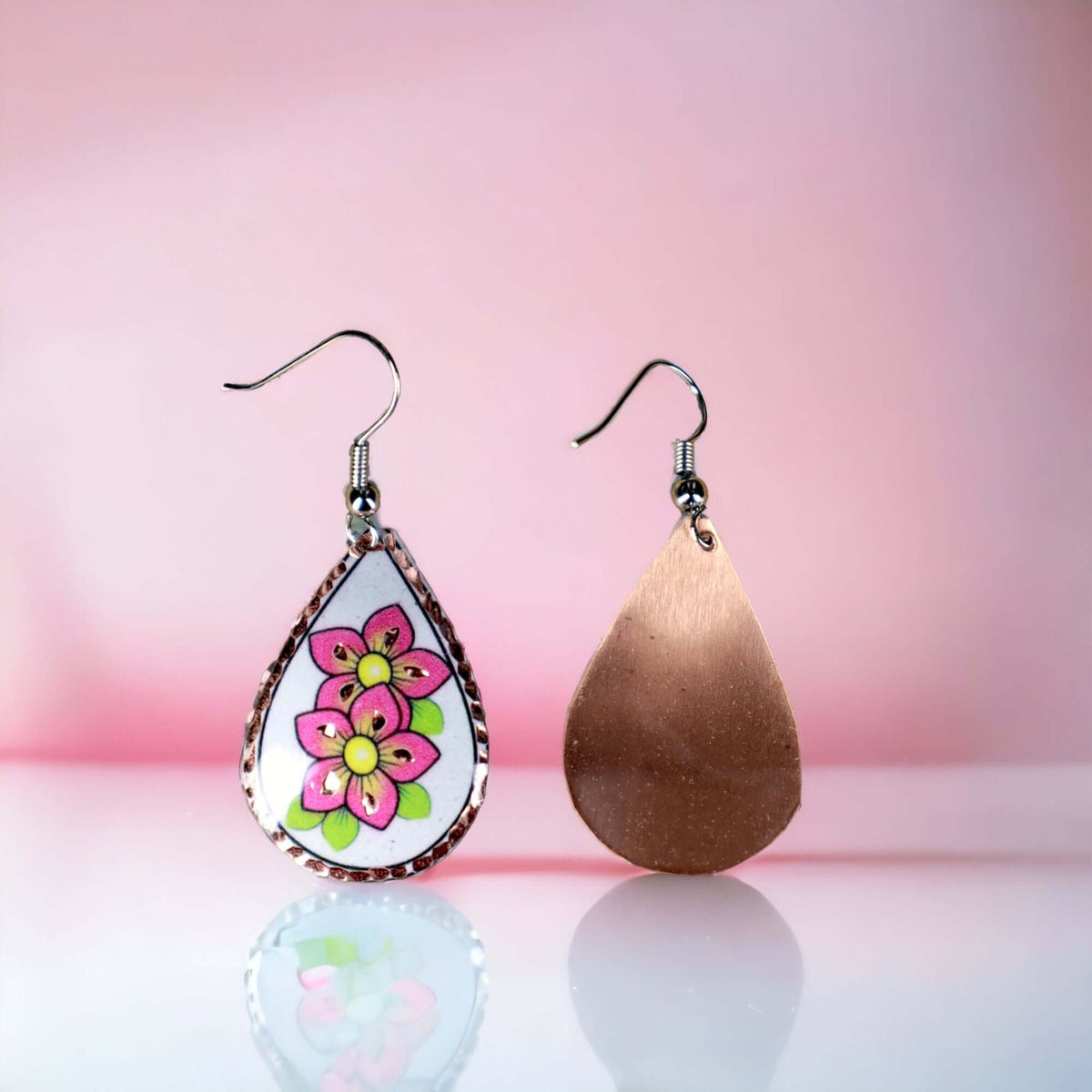 Angled close-up of handcrafted pink flower copper drop earrings