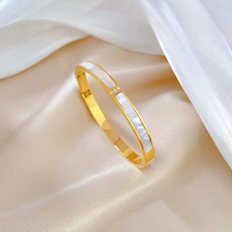 Gold and white bangle on a soft fabric background