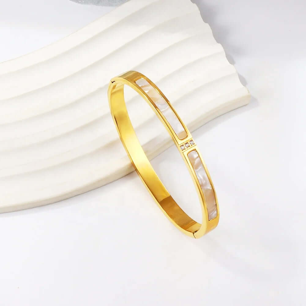 Gold bracelet on a white fabric background