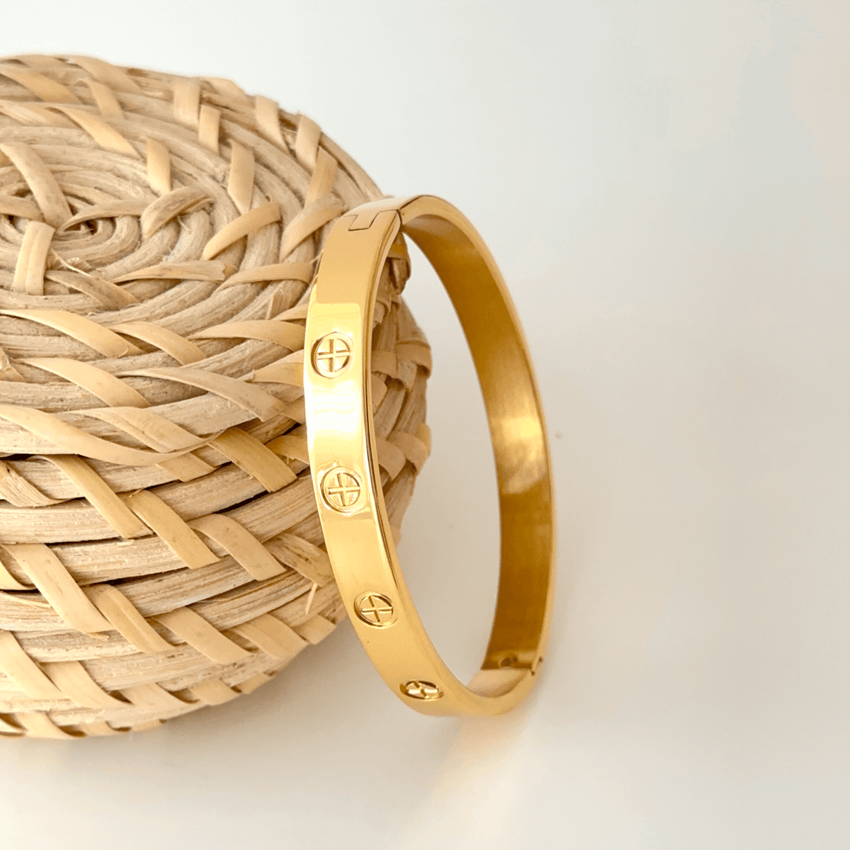 Gold plated stainless steel couple bangle shown next to a hand for scale