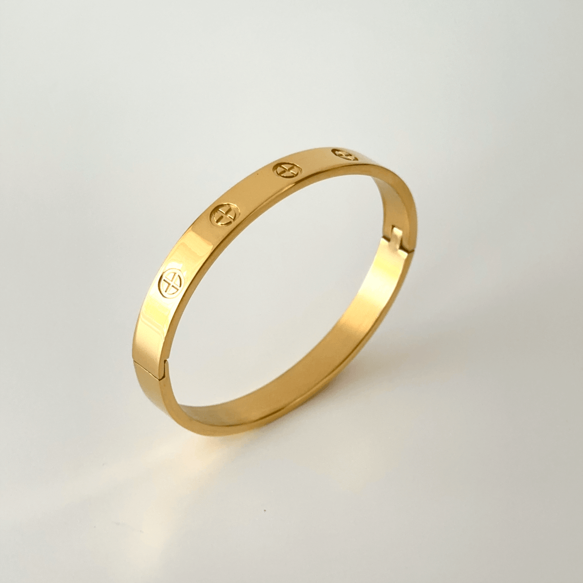 Gold plated stainless steel couple bangle displayed on a plain background