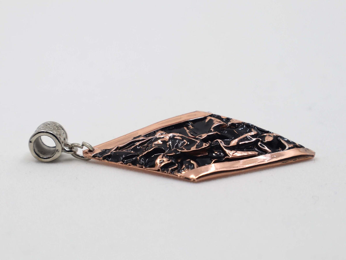 Handcrafted black wrinkled copper jewellery set shown next to a hand for scale