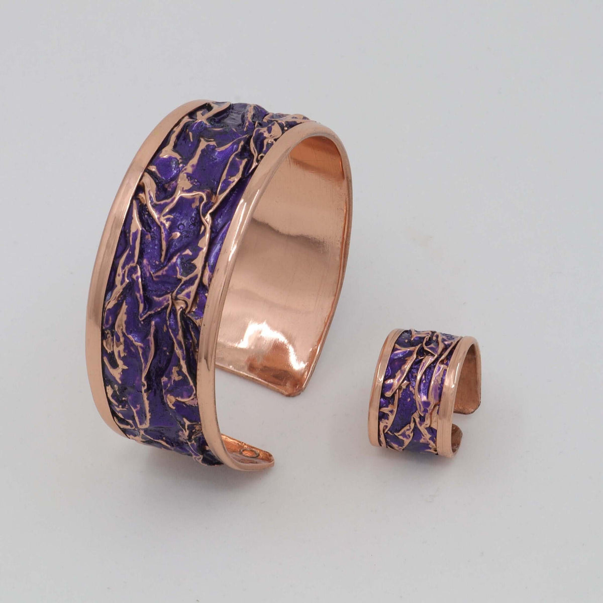 Four-piece purple wrinkled copper jewellery set shown next to a hand for scale