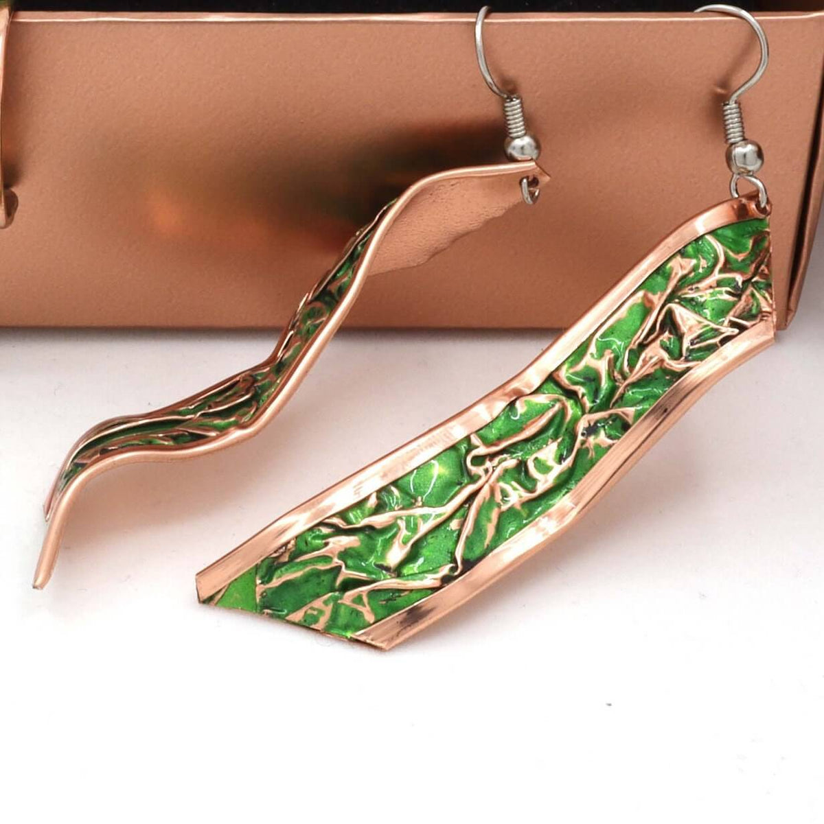 Angled close-up of handcrafted artisan green wrinkled copper earrings