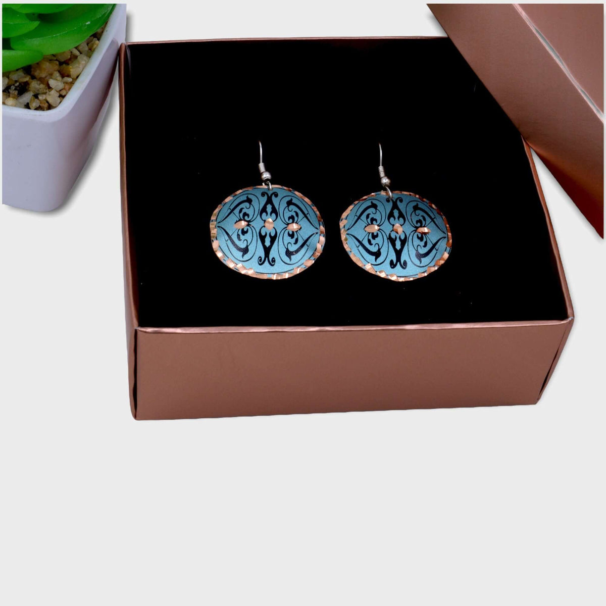 Handcrafted artisan green copper circle earrings worn on the ear