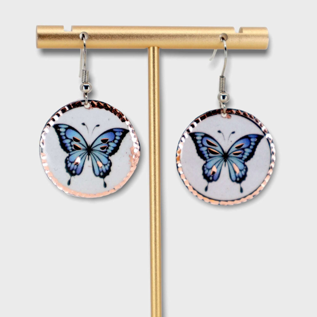 A pair of handcrafted butterfly copper circle earrings laid flat