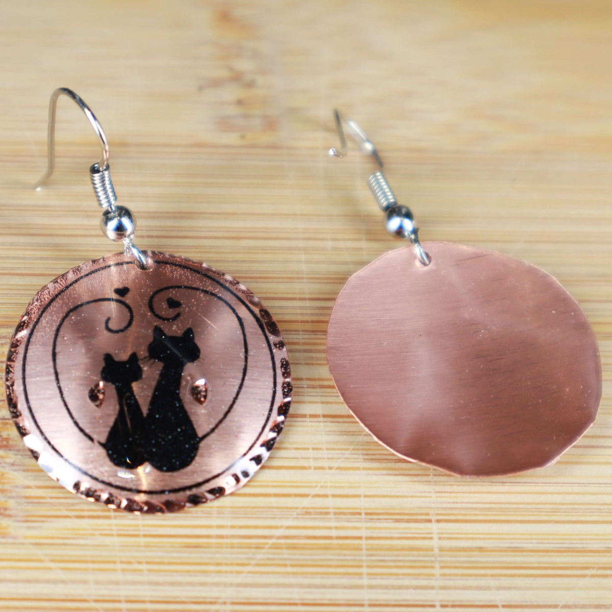 Handcrafted artisan cat design copper circle earrings worn on the ear