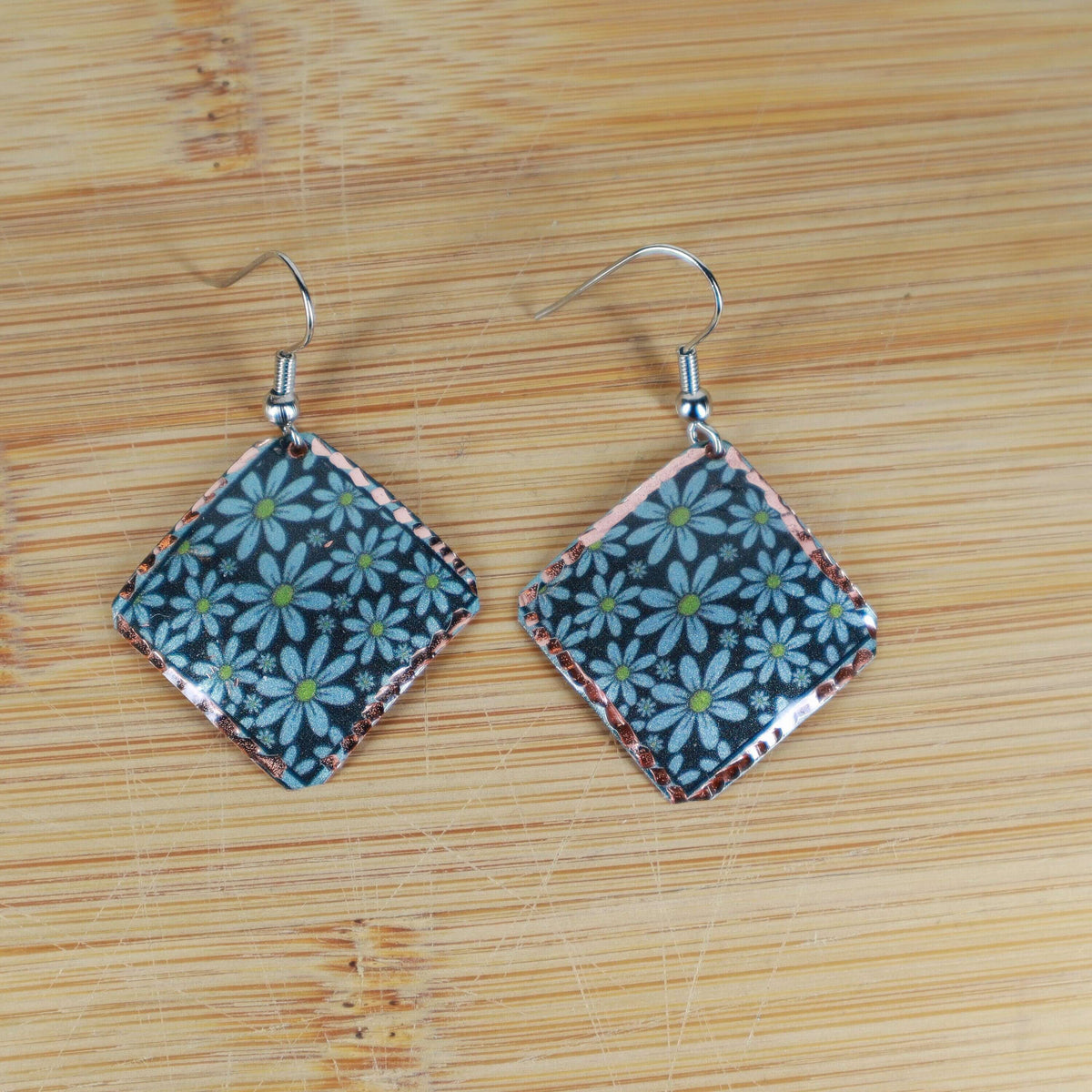 Artisan turquoise flower copper square earrings shown next to a hand for scale