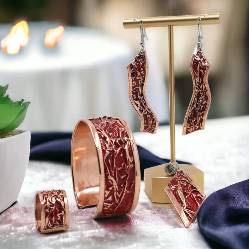 The full four-piece red patterned wrinkled copper jewellery set laid flat
