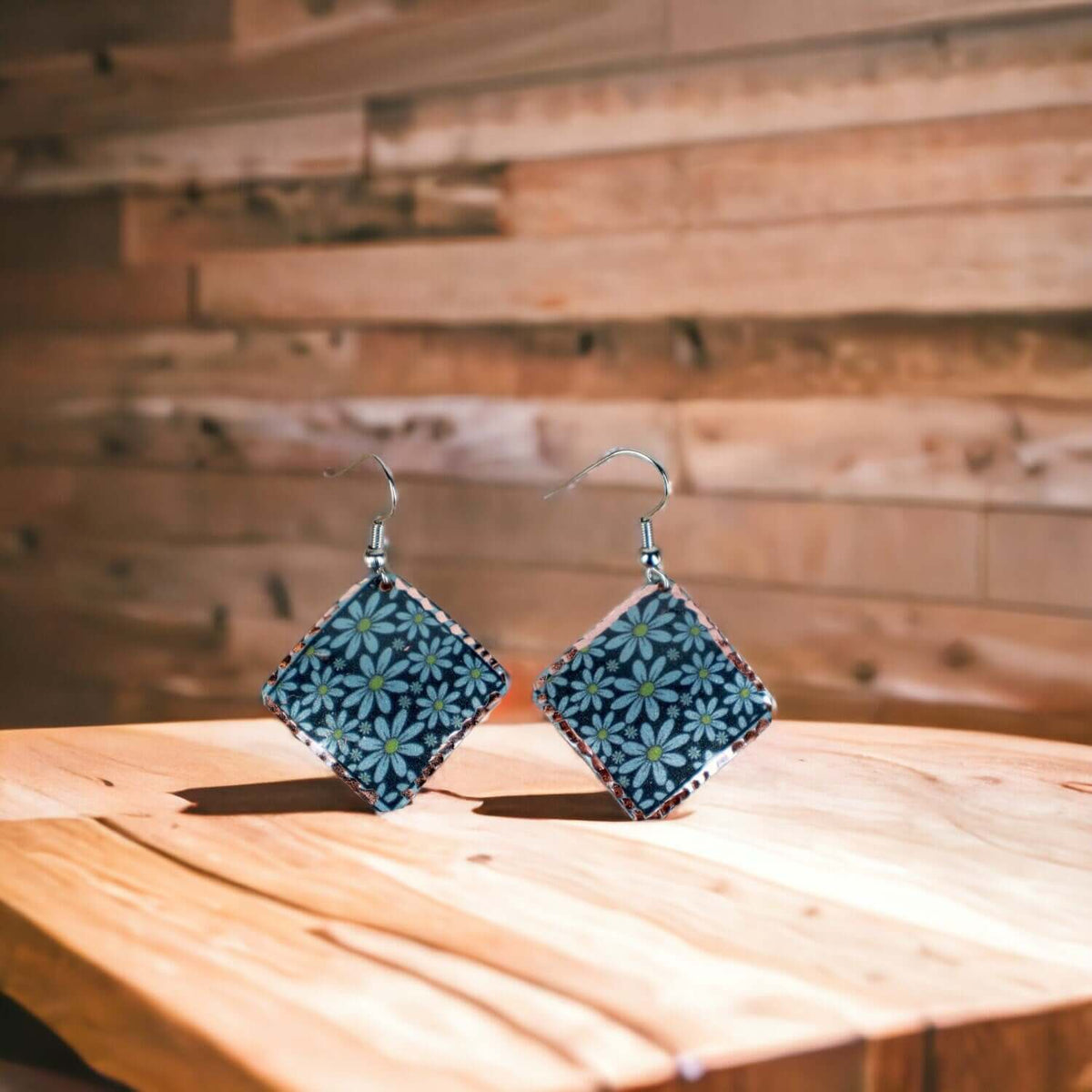 A pair of artisan turquoise flower copper square earrings laid flat