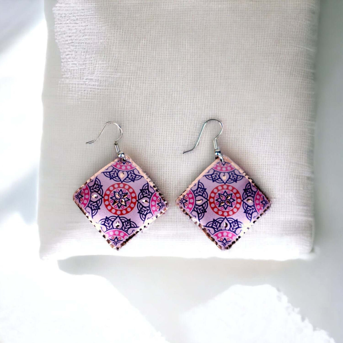 Side angle of handcrafted artisan pink copper square earrings