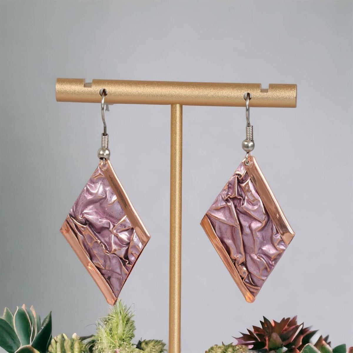 Handcrafted artisan wrinkled copper earrings worn on the ear