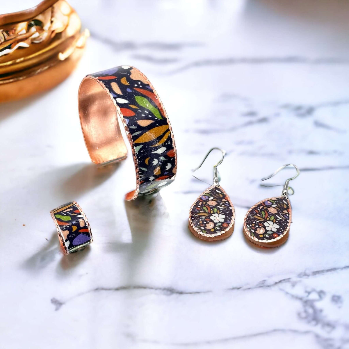 Top-down view of three-piece purple and white flowers copper jewellery set